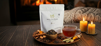 Tea packaging with a cup of tea, spices, and candles on a wooden table.